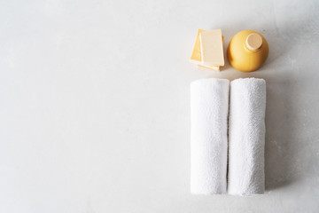 Spa concept: beautiful ceramic bottle, handmade organic soap, white towels on concrete light surface with copy space, flat lay.