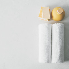 Spa concept: beautiful ceramic bottle, handmade organic soap, white towels on concrete light surface with copy space, flat lay.