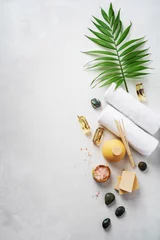 Rolgordijnen Flat lay spa composition with palm tropical leaf, towels, aroma fragrance bottle, handmade organic soaps, oil frangipani, sandal wood, patchouli, pink salt on light concrete surface with copy space. © PINKASEVICH