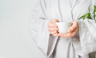 Close view of female hands holding teacup during tea ceremony with selective focus. Asian food theme background. Brewing and Drinking tea.