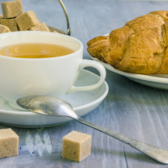 A cup of green tea and pieces of cane sugar on a wooden table