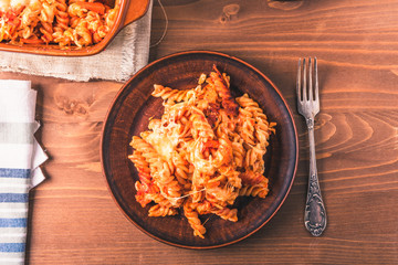 Traditional Italian pasta baked with mozzarella cheese and tomatoes on a plate and rustic background