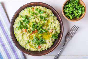 Traditional Italian vegetarian risotto with peas, carrots and parsley in rustic style, closeup