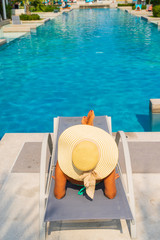 Fototapeta na wymiar Woman relaxing at the swimming pool at the luxury resort