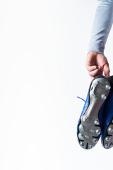 Football soccer player holding football boots cleats in hand on white background with copy space.