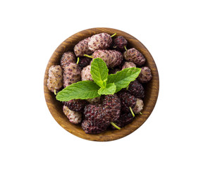 Mulberries in a wooden bowl with copy space for text. Black and purple mulberry on white background. Ripe and tasty mulberry isolated on white background. Top view.