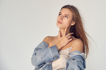 young woman looking up over gray background, studio - Image. Daydreaming and Thinking of Something Happy - Image. satisfied face