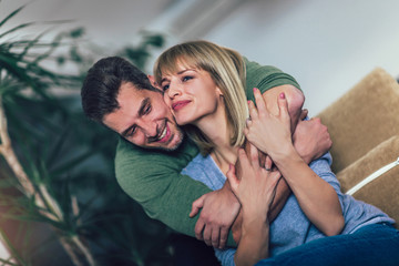 Loving young couple hugging and relaxing on sofa at home, selective focus.