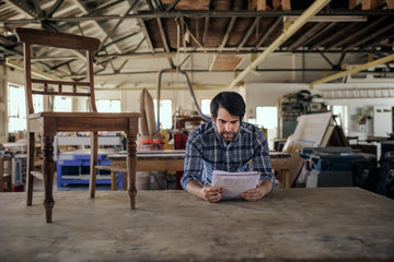 Woodworker creating a new chair design in his furniture workshop