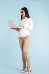 Business woman isolated over blue wall background using laptop computer.