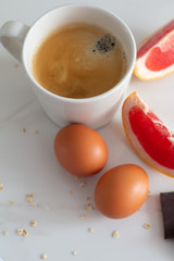 slices of grapefruit, eggs, slices of chocolate and coffee on a white background.