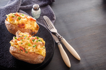 Baked potatoes with bacon and mushrooms in a rustic style in a black plate. Close-up. Copy space