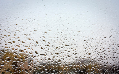 Raindrops on glass, window background view of buildings out of focus.