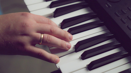 Closeup details man hands playing on piano. On guy finger wedding ring