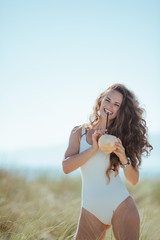happy young woman on beach drinking from coconut