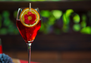 Red cocktail decorated with orange slice. Refreshing holiday aperitif for Christmas party.