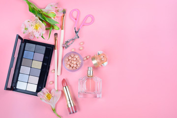 Сosmetics and flowers on pink background. Top view.