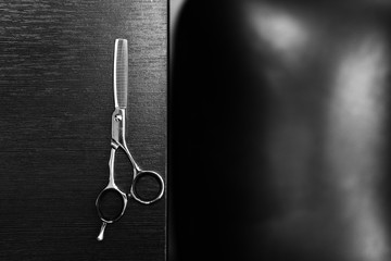 Fototapeta na wymiar scissors for highlighting on a dark wooden table. Hairdressing Workspace. Work place for hairdresser. Professional Salon Supplies. Hair. Place for text. copy space, black and white