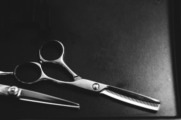 scissors for highlighting on a dark wooden table. Hairdressing Workspace. Work place for hairdresser. Professional Salon Supplies. Hair. Place for text. copy space, black and white