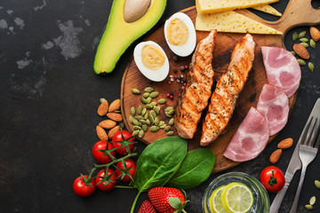 Keto lunch or dinner - grilled salmon, vegetables, boiled egg, water with lime, nuts, ham and...