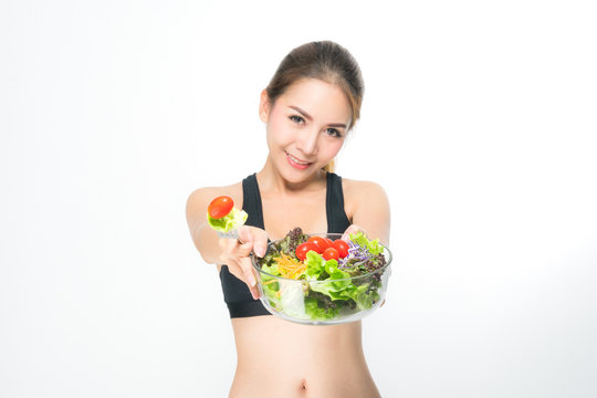 Asian girl(ages 20-30 years) in fitness suit eating salads on a white background.