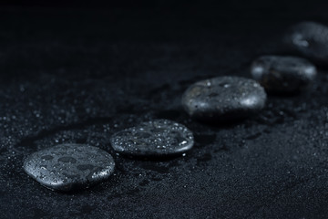 Fototapeta na wymiar Zen stones with drops of dew on a black background