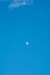A beautiful moon on a daytime blue, magical sky with white clouds