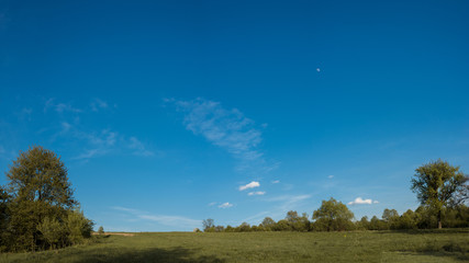 A beautiful moon on a daytime blue, magical sky with white clouds