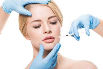 cropped shot of cosmetologists in medical gloves making beauty injection to young woman isolated on white