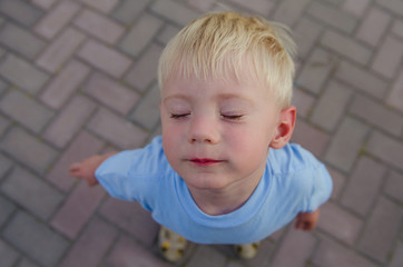 little boy raised his head up with closed eyes
