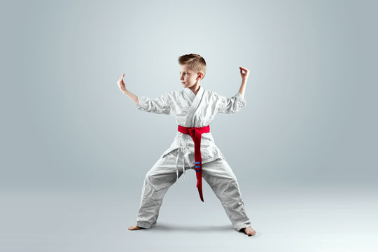 Creative Background, A Child In A White Kimono In A Fighting Stance, On A Light Background. The Concept Of Martial Arts, Karate, Sports Since Childhood, Discipline, First Place, Victory. Copy Space.