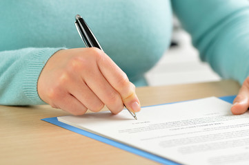 Close up front view portrait of a hand signing a contract on a desktop at office