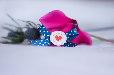 Close-up: Symbol of Love Heart in a Round Frame With a Ribbon in Front of Blurry Pink and Grey Fresh Flowers on a White Background. Concept: Romantic Bouquet With Love. 