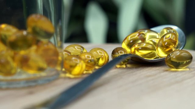 Omega 3 gold fish oil capsules on a spoon. Fatty acids, Vitamins minerals pills with fish oil on table. 3840X2160 UHD