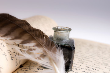 Old writing feather and ink spot with handwritten letter in background