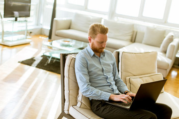 Man working on his laptop at home as he relaxes on a comfortable sofa