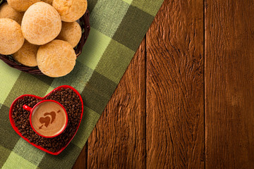 Cheese buns and Red cup and coffee saucer in heart shape with decorated coffee on old wood background. Top View. Heart shape in coffee.