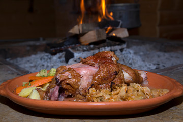 Serbian Specialty-Cooked Lamb In The Oven Served With Vegetables In Clay Plate Close Up, Open Fire In The Background