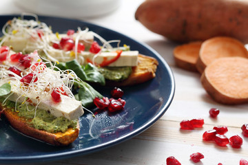 Pieczone bataty z zielonym pesto, tofu i kiełkami.