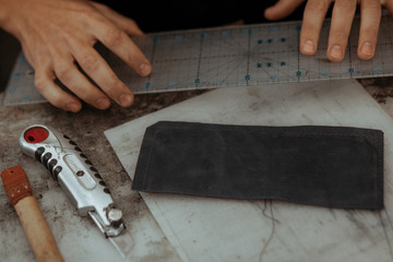 Close up of leather craftsman working with natural leather. Handmade master at work in local workshop. Handmade concept.