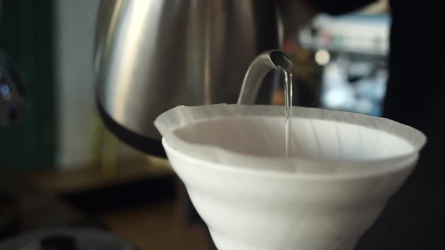 pouring hot water to the funnel due preparing the drip coffee