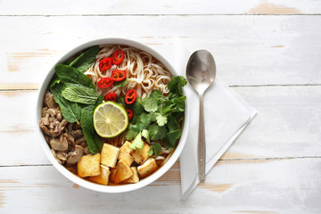 Apetyczna zupa.Makaron ryżowy w bulionie warzywnym z boczniakami, tofu i świeżymi ziołami.  © foodandcook