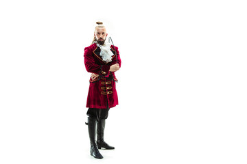 The young man wearing a traditional medieval costume of marquis posing at studio with whip....