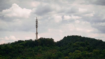 Obraz premium Aerial view of communication Tower on top of hill with clouds