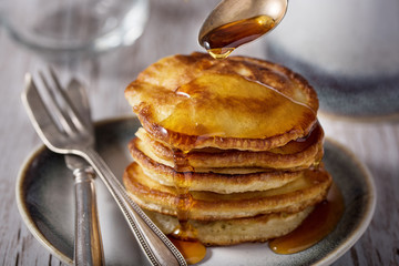 Shrove Tuesday, pancake day.  Pancakes poured with honey on the background of vintage plates, forks and knives. Shrovetide.