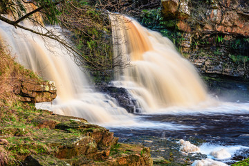 Fototapeta na wymiar Crammel Linn Waterfall on River Irthing, as the river flows over the 10 metre falls it marks the boundary between Northumberland and Cumbria just north of Gilsland, England