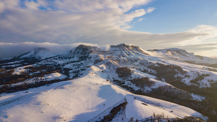 Aerial view of snow capped mountains during sunset