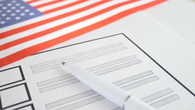 White pen lying on voting ballot paper with vote checkbox place and USA flag. Concept for voter registration and participation in elections in United States