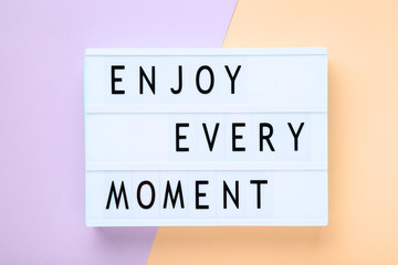 Lightbox with words Enjoy Every Moment on colorful background