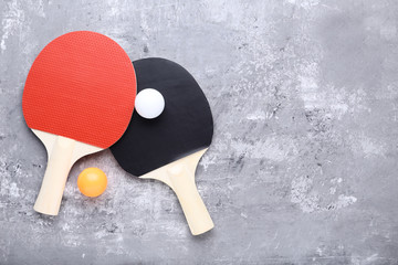 Table tennis rackets with balls on grey wooden table